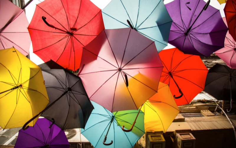Bunte Regenschirme, die über einer Straße hängen und die im Sonnenlicht von unten fotografiert wurden